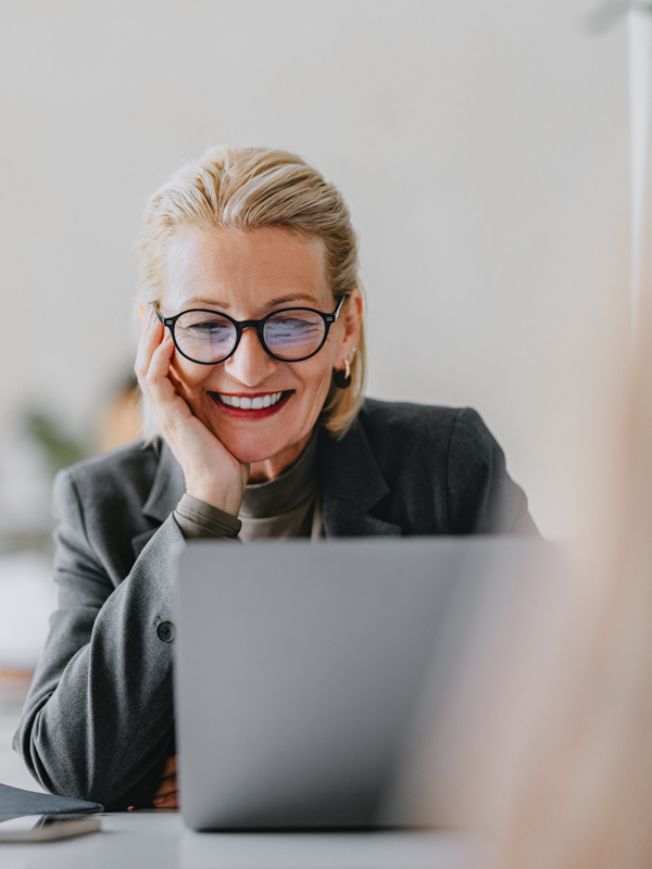 eine Frau mit Brille sitzt vor ihrem Laptop